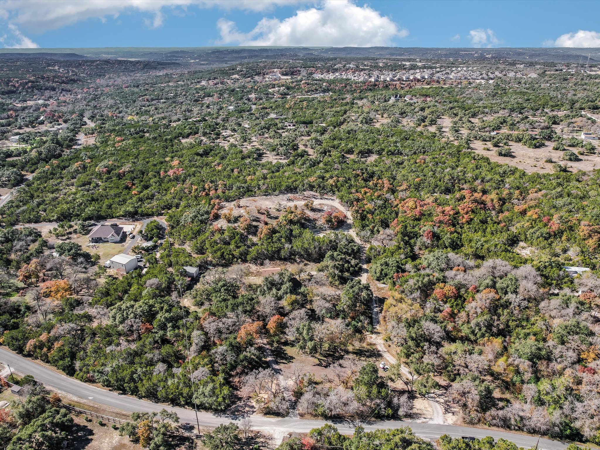 13404 Cedar Lime Road Leander, TX 78641 - Photo 1 of 28 A sweeping aerial view reveals a verdant landscape of trees and a winding road, promising secluded living.