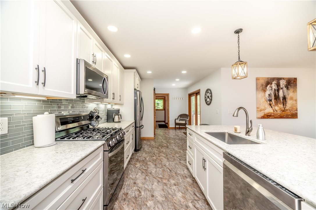 405 Airport Road Northwest Warren, OH 44481 - Photo 12 of 50 Kitchen featuring white cabinetry, light countertops, stainless steel appliances, featuring a glass tile backsplash.
