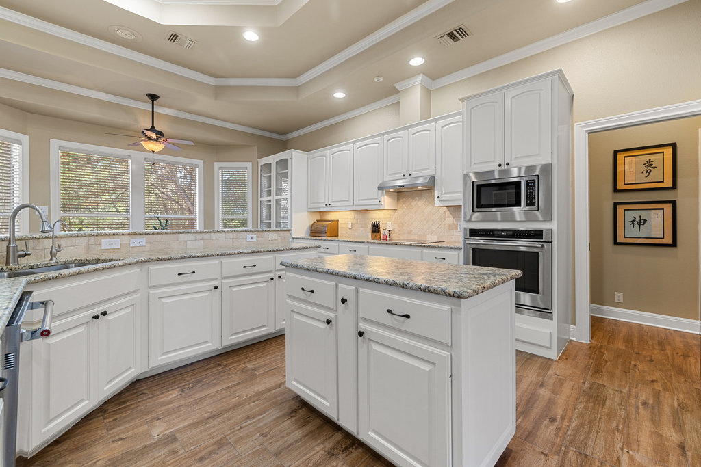 3507 Bee Creek Road Spicewood, TX 78669 - Photo 18 of 40 a kitchen with granite countertop white cabinets and white appliances