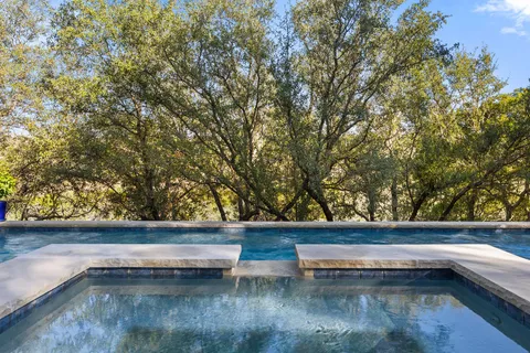 a view of small pool with lawn chairs under an umbrella