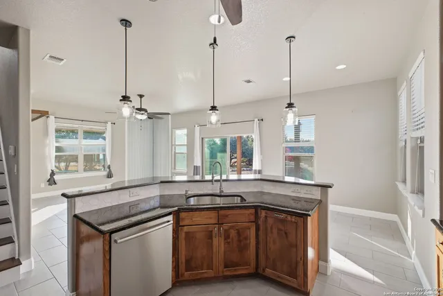 a kitchen with stainless steel appliances granite countertop a sink a window and wooden floor