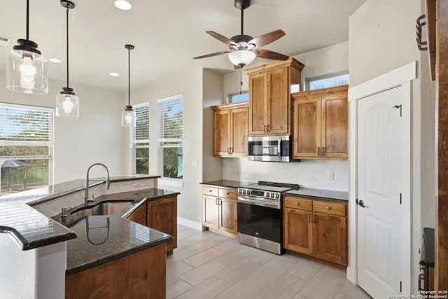 a kitchen with stainless steel appliances granite countertop a sink a stove and a refrigerator