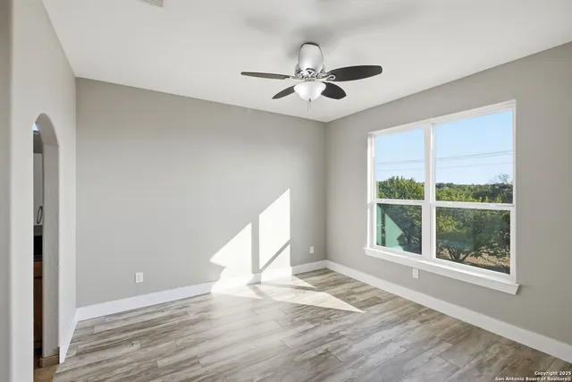 a view of an empty room with wooden floor and a window