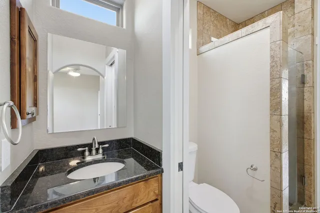 a bathroom with a granite countertop sink toilet and shower