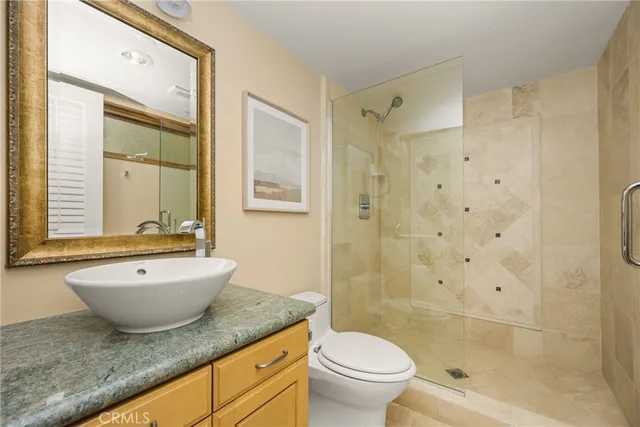 a bathroom with a granite countertop sink toilet mirror and shower