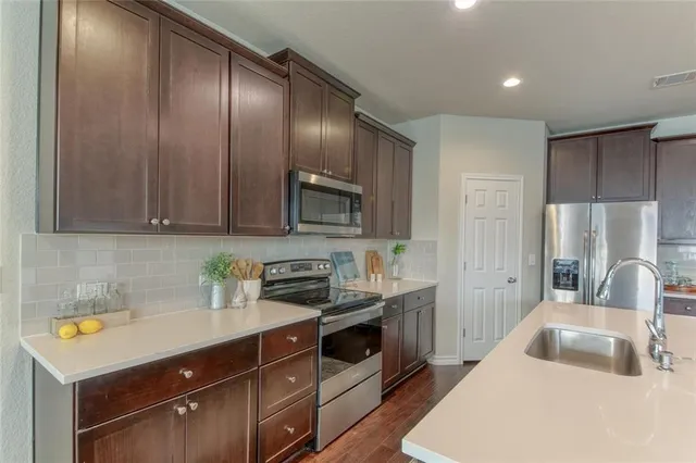 a kitchen with a sink a stove a refrigerator and cabinets