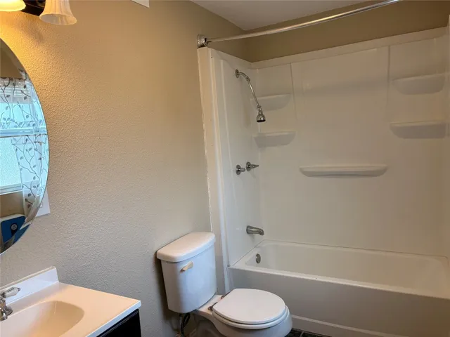 a white toilet and tub sitting next to a bathroom sink