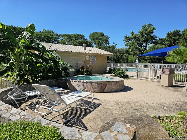 a view of a swimming pool with lawn chairs under an umbrella