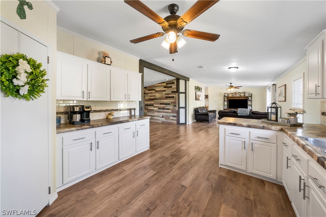 2401 Wendy Road Fort Denaud, FL 33935 - Photo 20 of 35 a kitchen with stainless steel appliances kitchen island granite countertop a stove top oven a sink a dining table and chairs with wooden floor