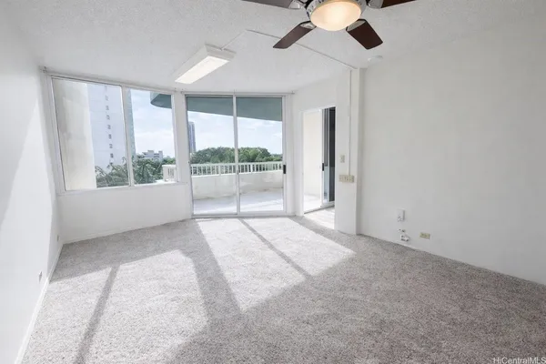 an empty room with windows chandelier fan and windows