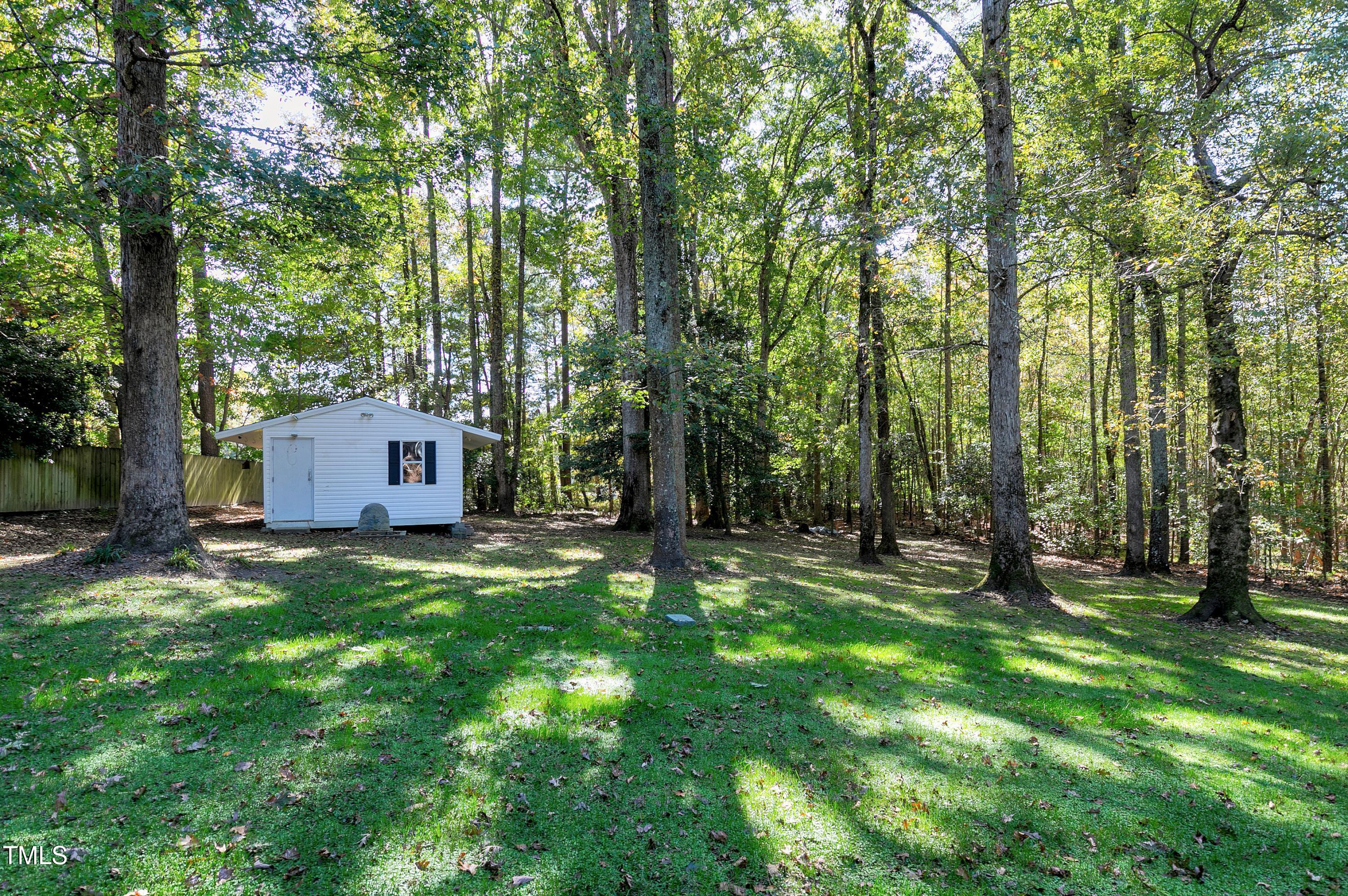 7834 James Austin Road Willow Spring, NC 27592 - Photo 45 of 46 a backyard of a house with lawn chairs and a large tree