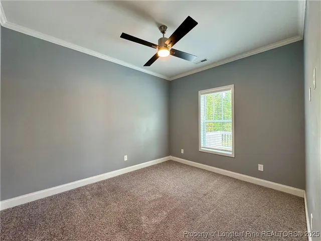 an empty room with ceiling fan and windows