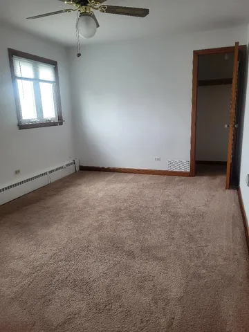 an empty room with a chandelier fan and windows