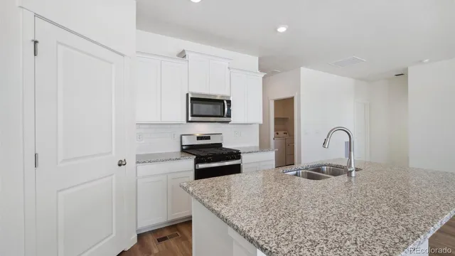 a large kitchen with granite countertop a stove a sink and a microwave