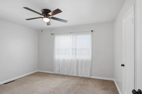 an empty room with chandelier fan