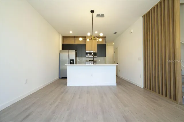 a large kitchen with stainless steel appliances a large center island attached withe living room