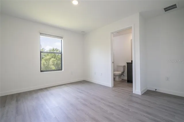 an empty room with wooden floor and windows