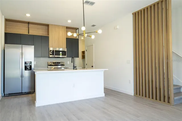 a kitchen with kitchen island a counter top space stainless steel appliances and a ceiling fan