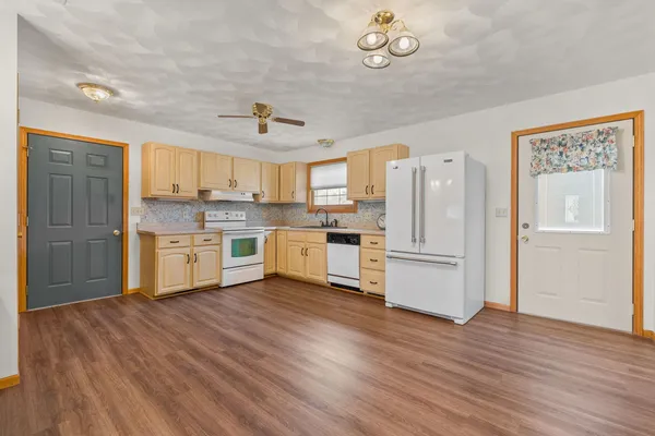 a kitchen with stainless steel appliances a refrigerator a sink dishwasher a stove and white cabinets with wooden floor