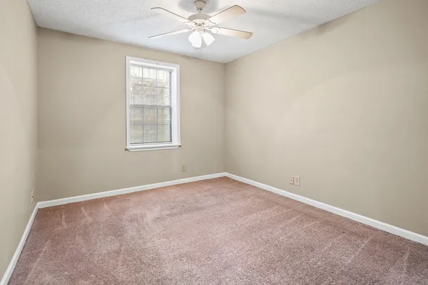 an empty room with windows and fan