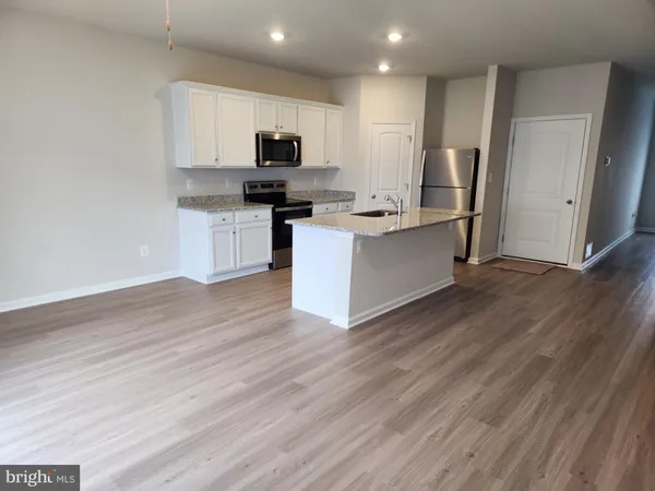 a kitchen with granite countertop a sink cabinets and wooden floor