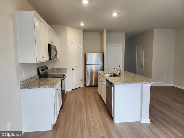 a kitchen with kitchen island granite countertop a sink and wooden floor