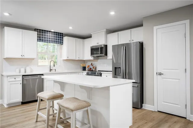 a kitchen with a refrigerator a stove a sink and chairs