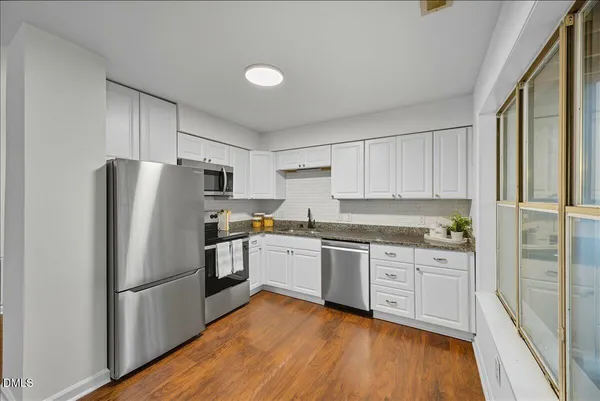 a kitchen with granite countertop stainless steel appliances a refrigerator a sink and cabinets
