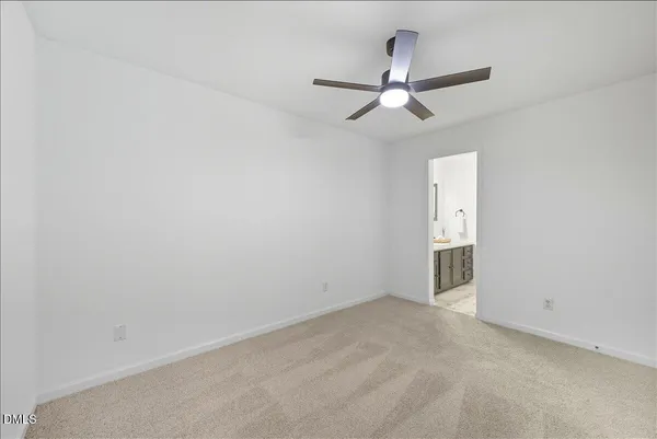 an empty room with a ceiling fan and carpet