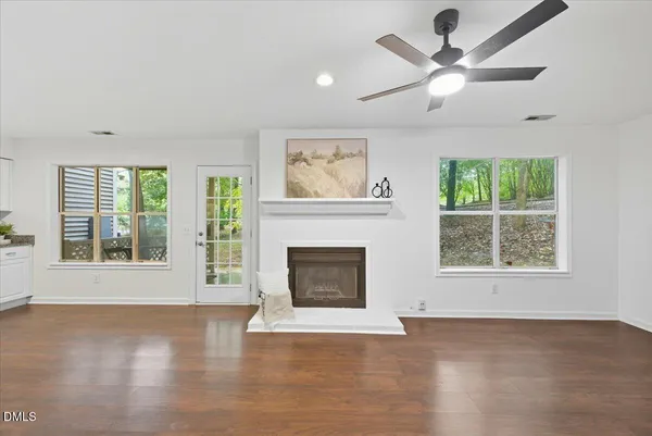 an empty room with windows fireplace and wooden floor
