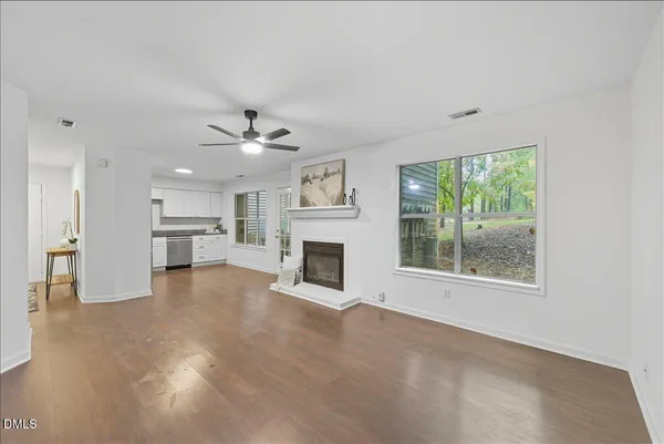 a view of a livingroom with a fireplace a ceiling fan and windows