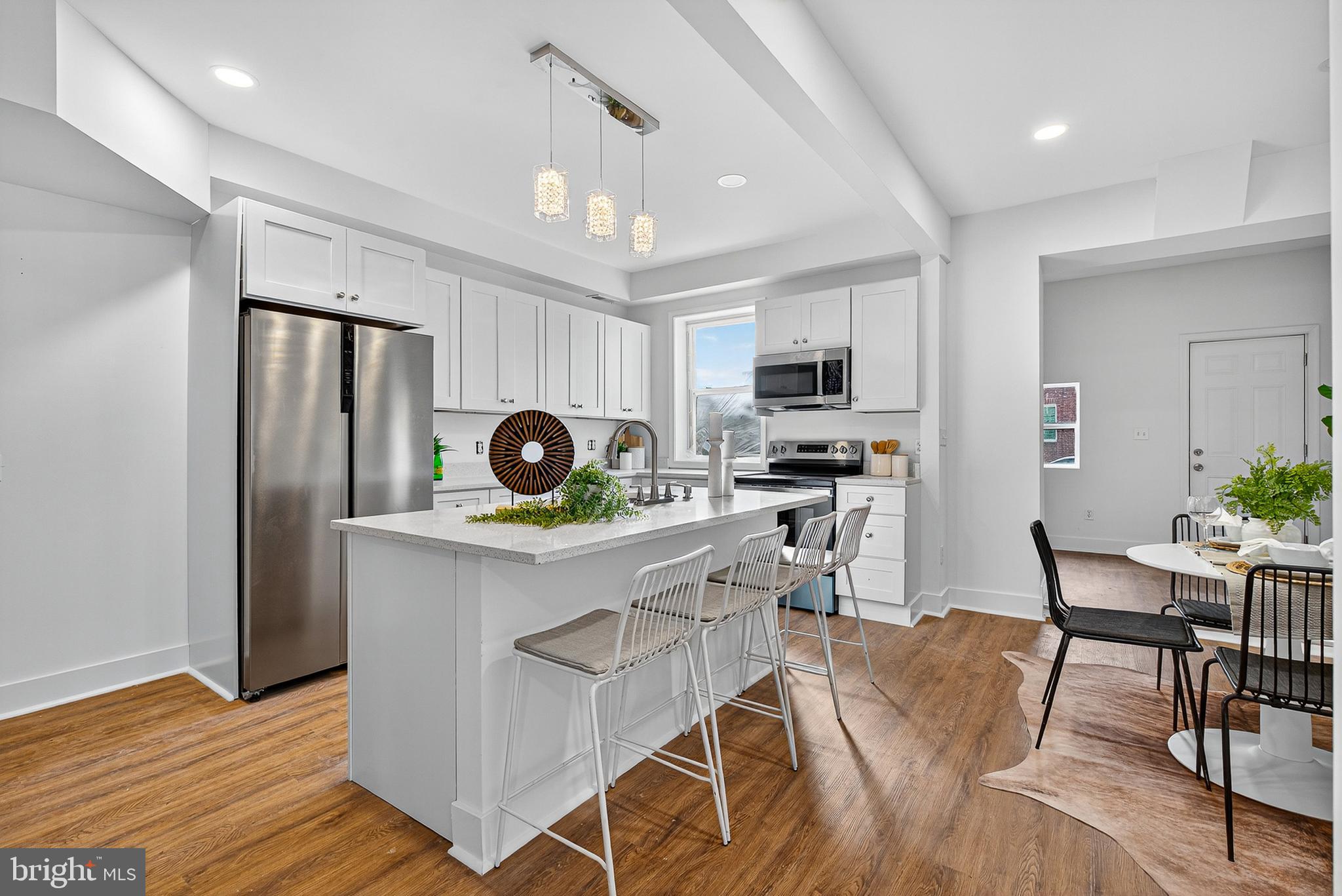 802 North Woodington Road Baltimore, MD 21229 - Photo 8 of 41 a kitchen with stainless steel appliances granite countertop a stove top oven a refrigerator a dining table and chairs with wooden floor