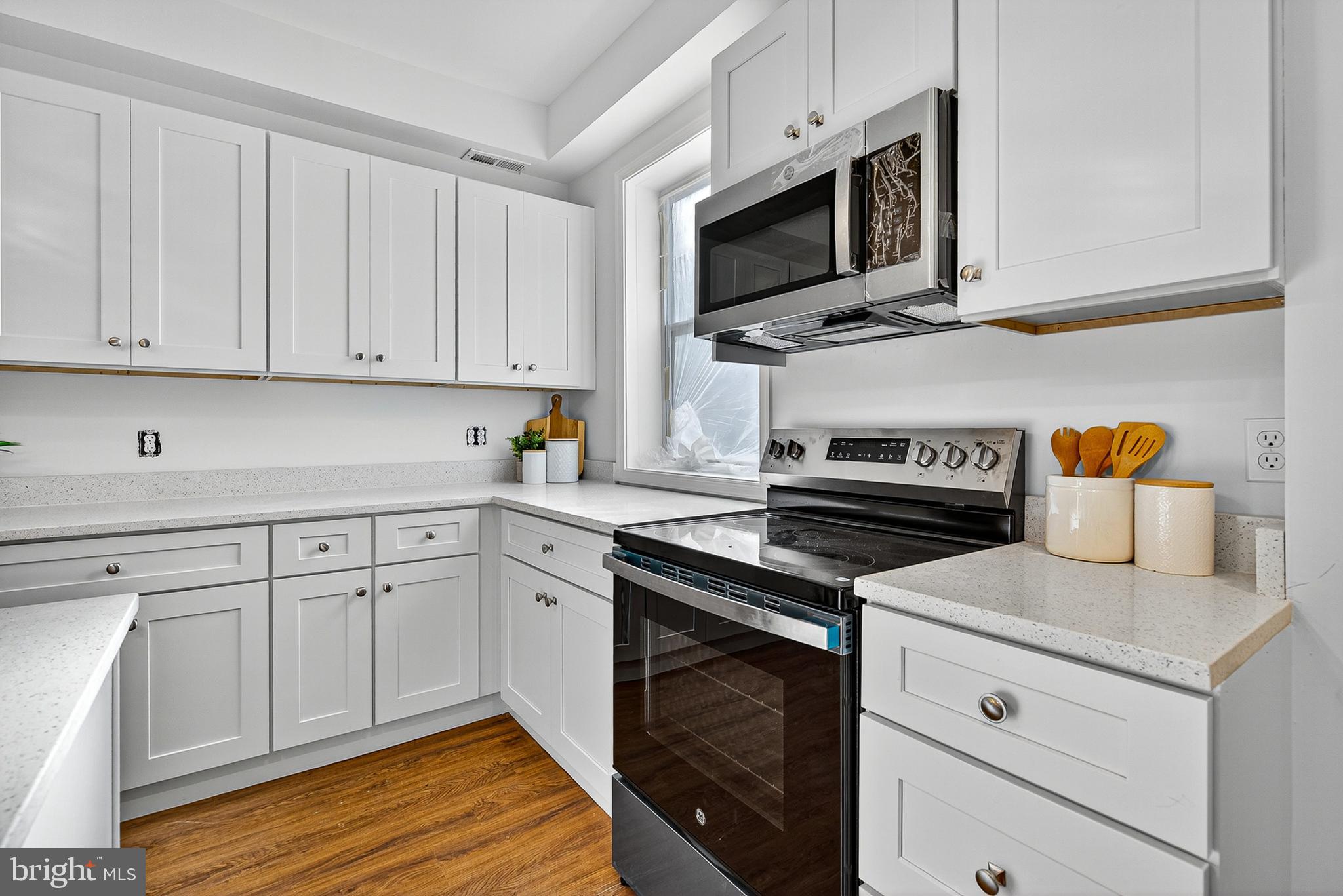 802 North Woodington Road Baltimore, MD 21229 - Photo 9 of 41 a kitchen with cabinets stainless steel appliances and wooden floor