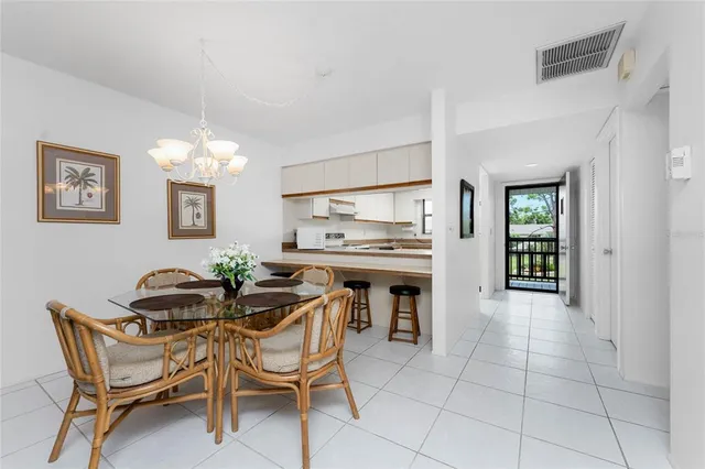 a dining room filled a chandelier and kitchen view
