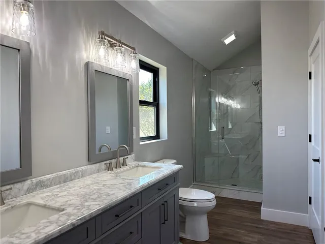 a bathroom with a granite countertop sink toilet a large mirror and shower