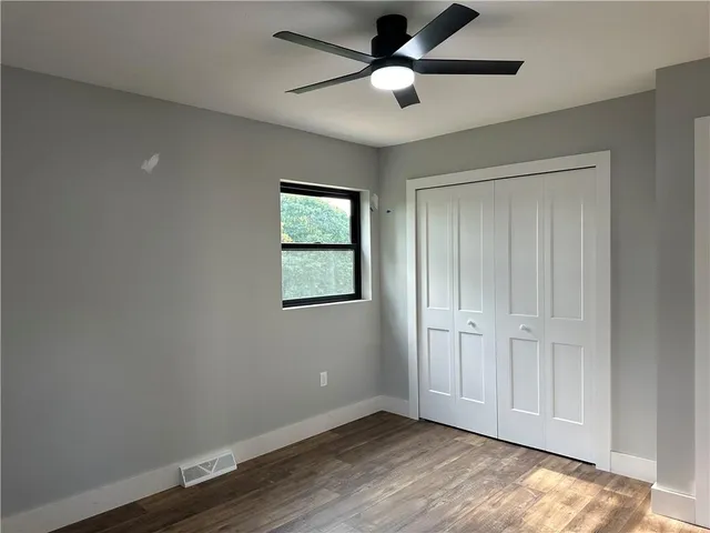an empty room with wooden floor closet and windows