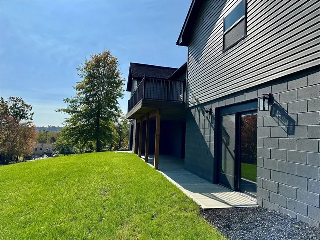 a view of a house with a small yard and a large tree