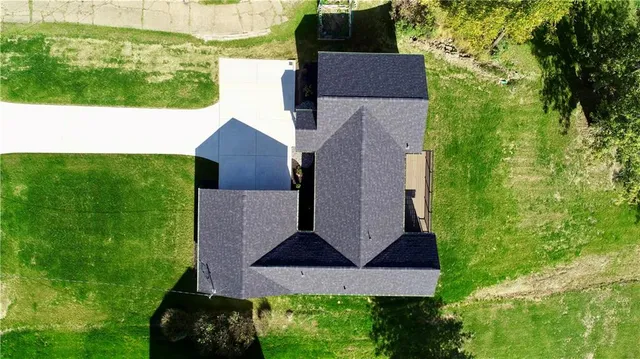 an aerial view of residential house with outdoor space and trees all around
