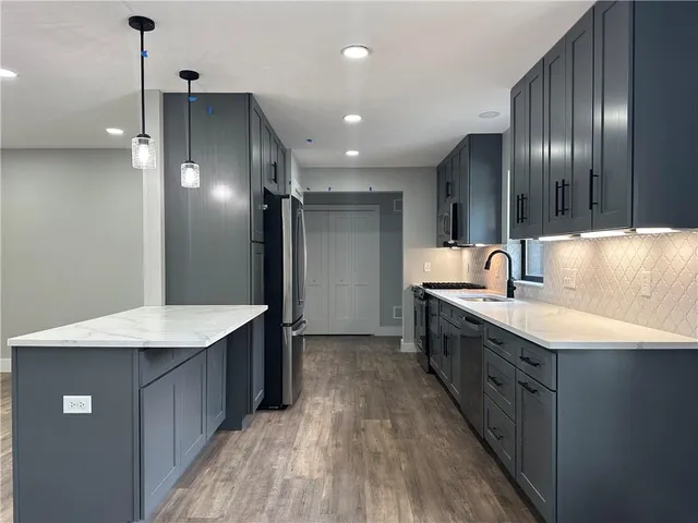 a kitchen with stainless steel appliances kitchen island granite countertop a sink refrigerator and cabinets