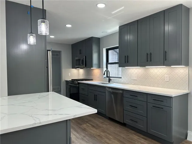 a kitchen with kitchen island granite countertop a sink cabinets and wooden floor