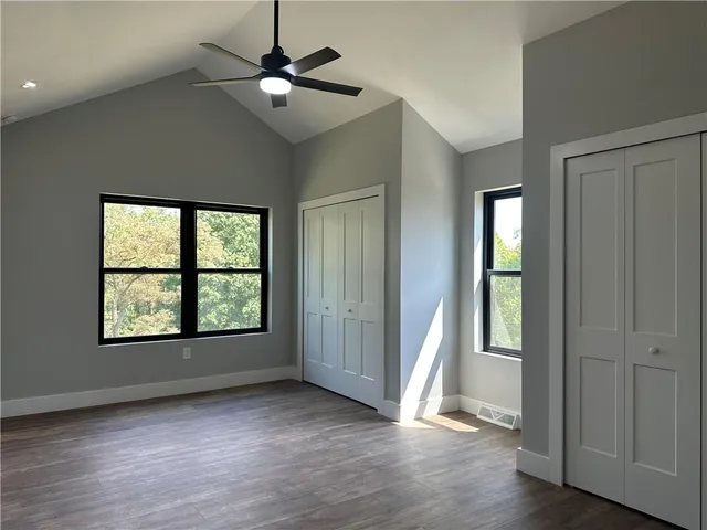 a view of an empty room with a window and wooden floor
