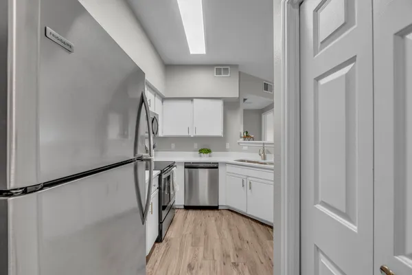 a view of a kitchen with a sink and dishwasher a refrigerator with wooden floor