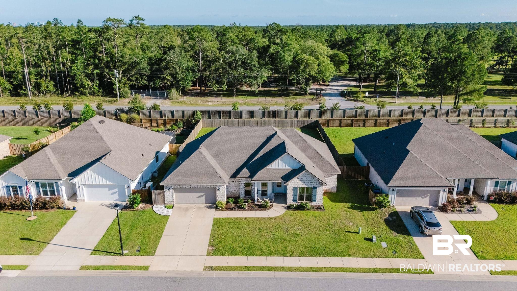 7872 Calverton Street Foley, AL 36535 - Photo 67 of 76 Contemporary single-story residence featuring a gray shingle roof, light brick facade, and a paved driveway leading to an integrated garage