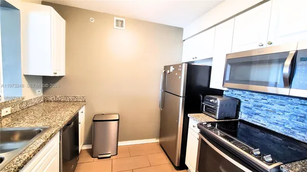 a kitchen with granite countertop a sink stove and refrigerator