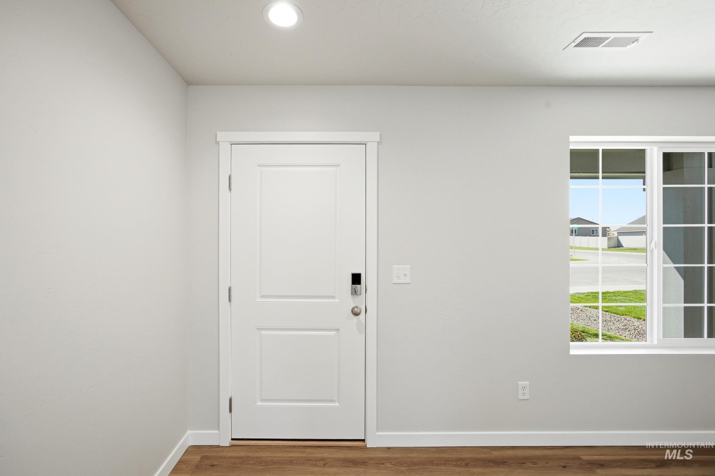 13333 Bank Street Caldwell, ID 83607 - Photo 2 of 29 Recessed ceiling lighting, wood-finish flooring, white two-panel door, window with grid pattern, and white trim throughout