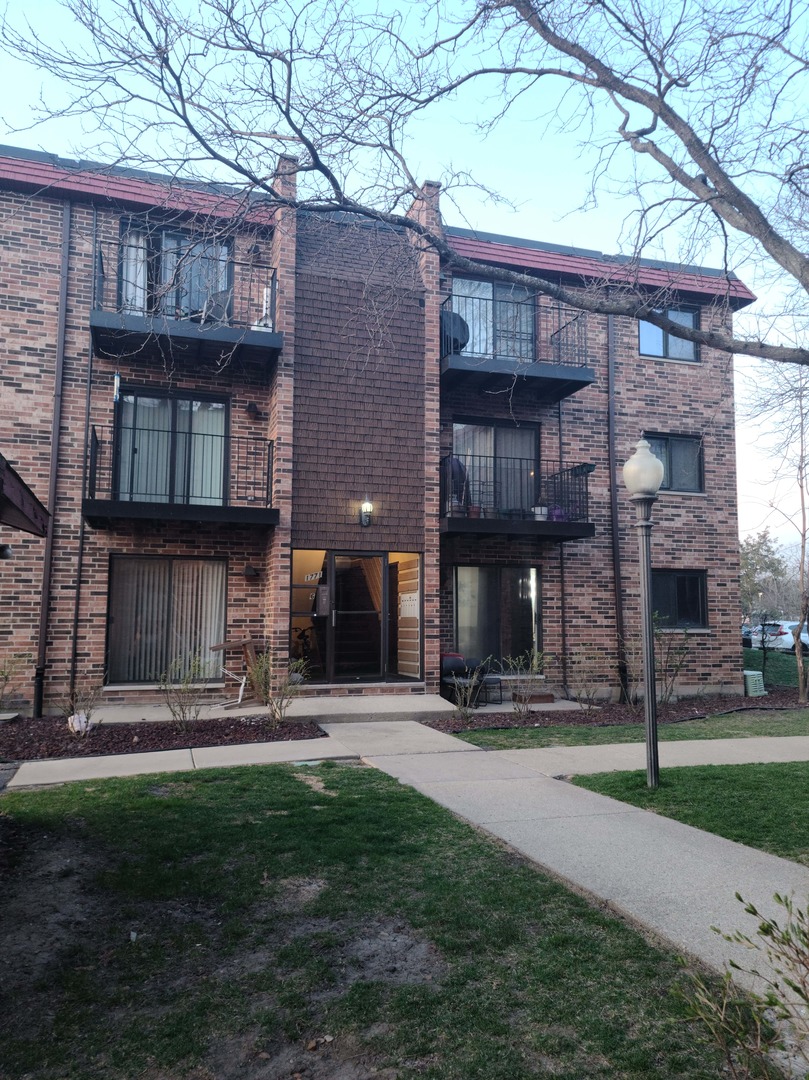1771 West Algonquin Road, Unit 3B Mount Prospect, IL 60056 - Photo 1 of 17 a front view of a house with yard and outdoor seating