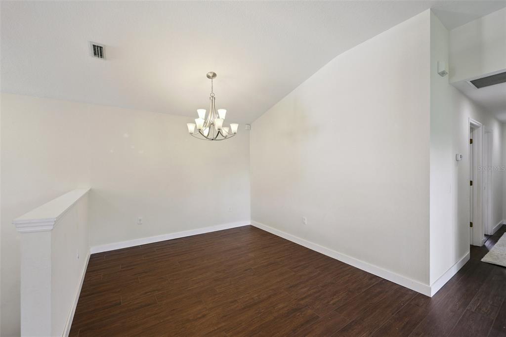 6412 Rosefinch Court, Unit 204 Lakewood Ranch, FL 34202 - Photo 12 of 33 an empty room with wooden floor and chandelier