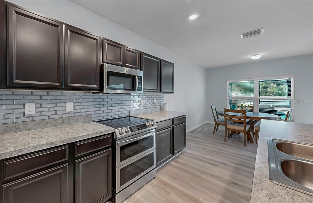 14530 Haddon Mist Drive Wimauma, FL 33598 - Photo 4 of 44 a kitchen with stainless steel appliances granite countertop a stove microwave and sink
