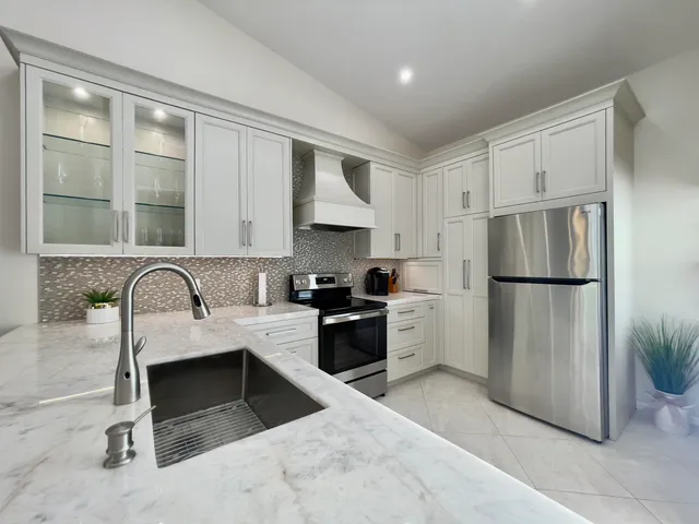 a kitchen with a refrigerator sink and white cabinets