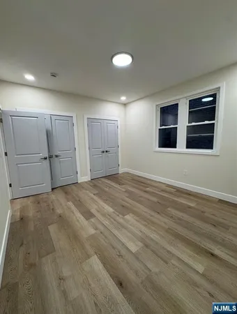 a view of empty room with wooden floor and window